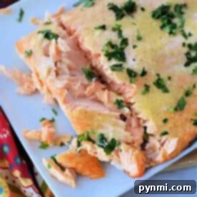 Frozen salmon in air fryer, cooked to perfection and garnished with chopped herbs on a white plate, partially flaked.