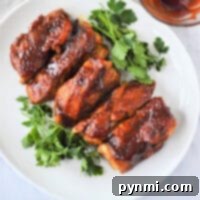 Country style pork ribs, tenderized in the Instant Pot, are glazed with sauce on a white plate, garnished with fresh parsley.
