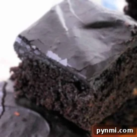 Close-up of a stack of chocolate brownies with a glossy, cracked top layer. Imagining these as part of a zucchini brownie recipe enhances their moist and dense texture, showcasing a rich, dark brown color.