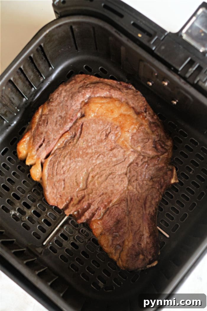 Succulent air fryer ribeye steak, perfectly seared on the outside and tender on the inside, resting before being sliced.