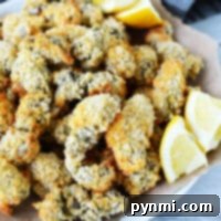 A plate of crispy air fryer oysters with lemon wedges served on brown parchment paper.
