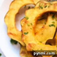 Perfect Air Fryer Acorn Squash 7 Sliced air fried acorn squash on a white plate, garnished with chopped herbs for a delightful flavor, reveals the magic of air fryer acorn squash.