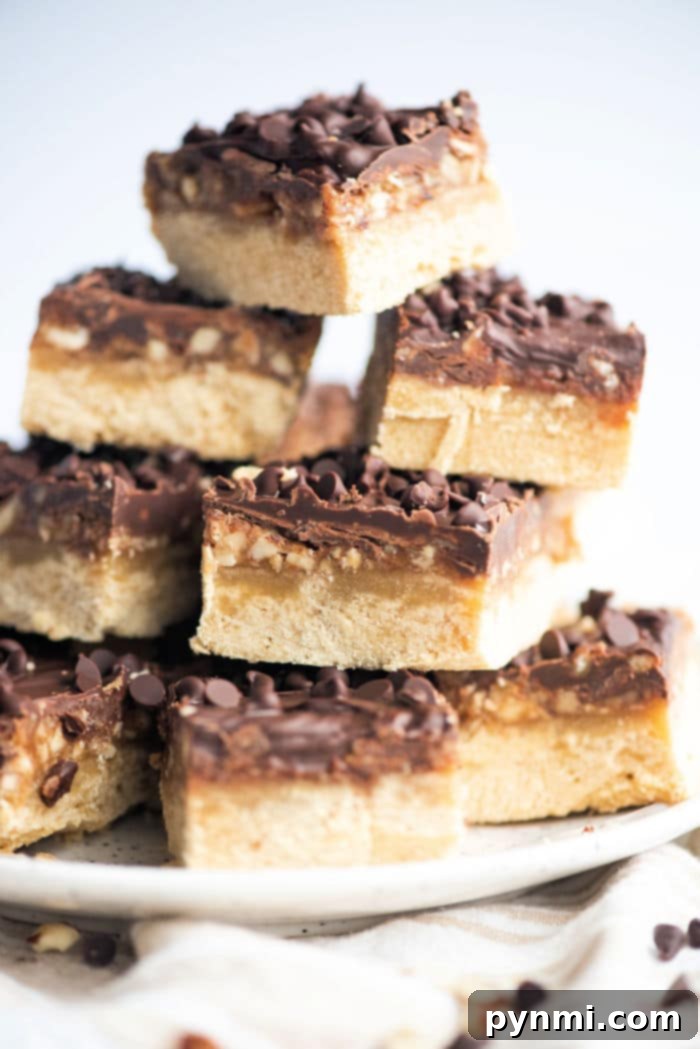 Buttery Pecan Shortbread Squares 5 A stack of chocolate and pecan shortbread bars, topped with crunchy nuts, arranged elegantly on a white plate, ready to be served.