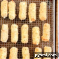 Homemade mozzarella sticks lined up on a wire rack, ready for the air fryer.