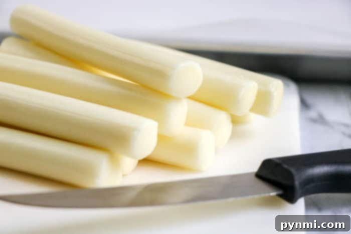 Crispy Homemade Air Fryer Mozzarella Sticks 6 Individual string cheese sticks, the primary ingredient for homemade mozzarella sticks, laid out on a clean surface.