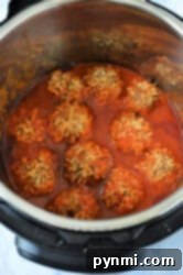 Effortless Instant Pot Porcupine Meatballs 8 An Instant Pot filled with porcupine meatballs in a rich red tomato sauce. The meatballs, perfectly cooked, are partially submerged, allowing a glimpse of the seasoned sides and bottom of the cooker.