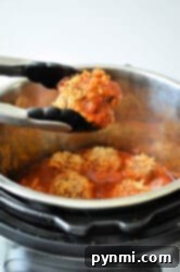 Effortless Instant Pot Porcupine Meatballs 9 Tongs holding a portion of porcupine meatballs in front of an Instant Pot filled with stuffed peppers in tomato sauce. The dish consists of ground meat and rice in red sauce.