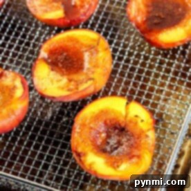 Halved peaches topped with brown sugar on a wire rack, ready to transform into air fryer peaches, set on a baking tray.