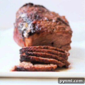 Sliced air fryer roast beef brisket on a white plate, featuring a crispy, seasoned outer layer.