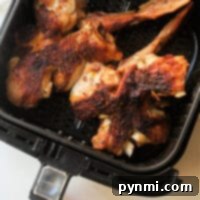 Close-up of grilled turkey wings inside an air fryer basket.