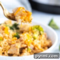 Lifting a forkful of delicious instant pot cheesy chicken and rice with broccoli from the bowl.