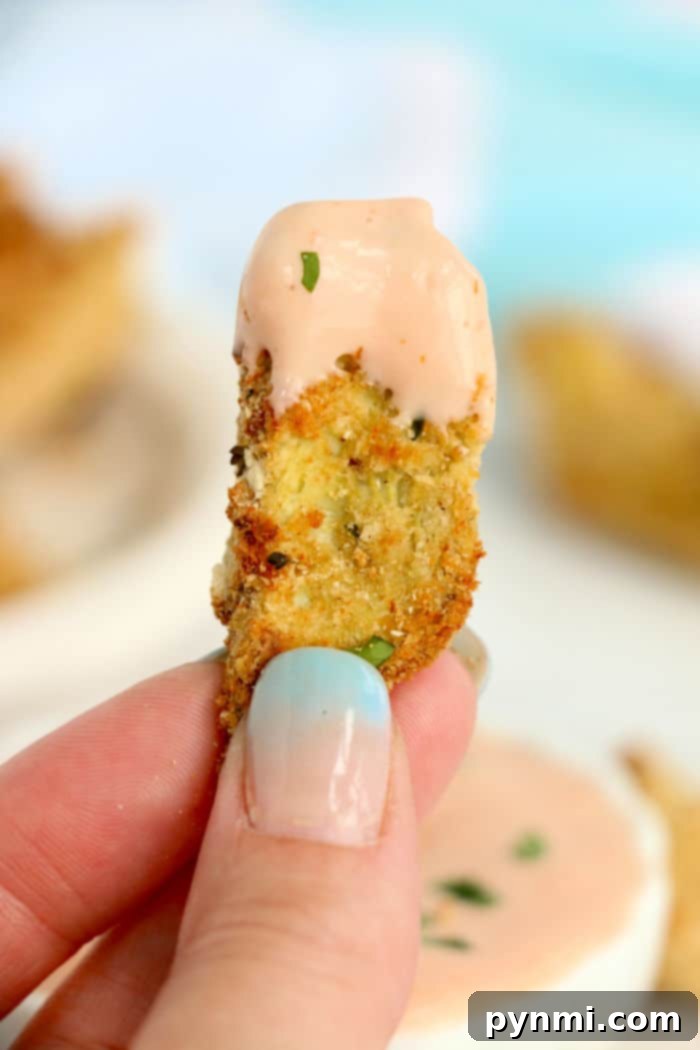 Close-up of a hand holding a breaded perfectly cooked air fryer artichoke hearts.
