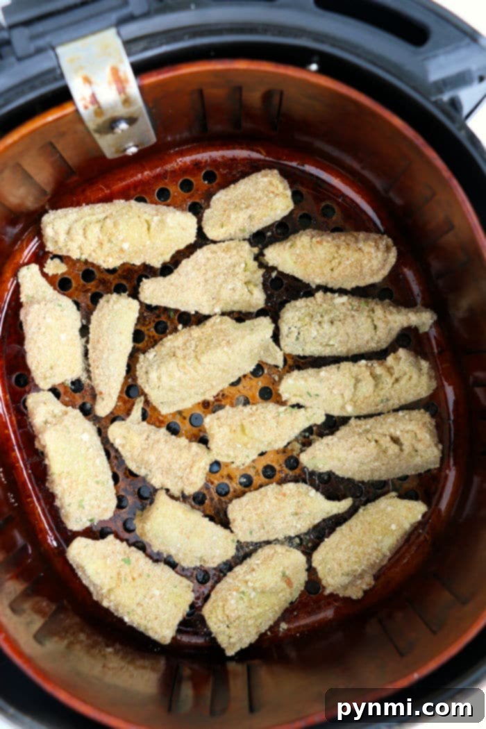 Crispy, breaded artichoke hearts are perfectly arranged alongside air fryer artichoke hearts in an air fryer basket.