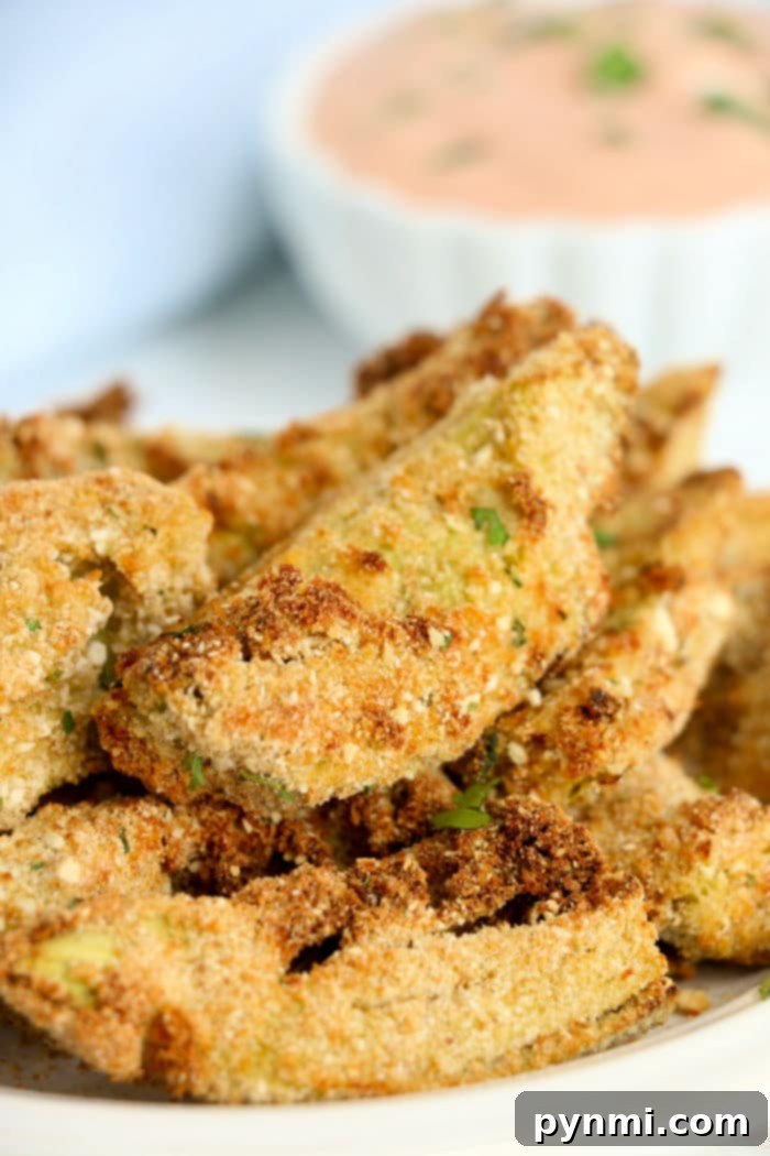 Close-up of crispy breaded artichoke hearts with a hint of air fryer artichoke hearts, accompanied by a dipping sauce in the background.