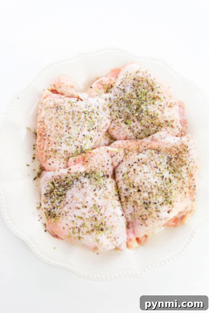 Juicy Garlic Butter Bone-In Chicken Thighs 3 Close-up of golden-brown chicken thighs seasoned with herbs, nestled in a cast iron skillet.