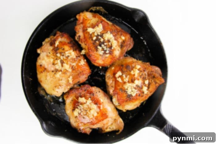 Juicy Garlic Butter Bone-In Chicken Thighs 4 Three perfectly golden-brown garlic chicken thighs arranged in a cast iron pan, ready to serve.