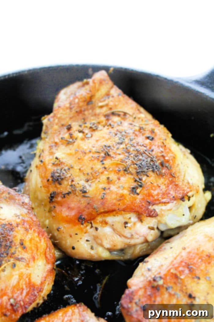 Juicy Garlic Butter Bone-In Chicken Thighs 5 Four garlic butter chicken thighs baked in a cast iron skillet, garnished with fresh parsley.