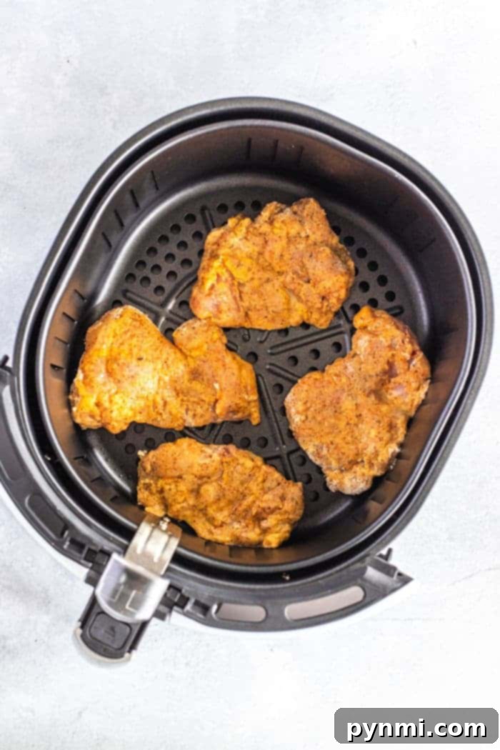 A vibrant close-up of air fryer fried chicken thighs, skinless and perfectly golden, ready to be enjoyed as a healthier meal option.