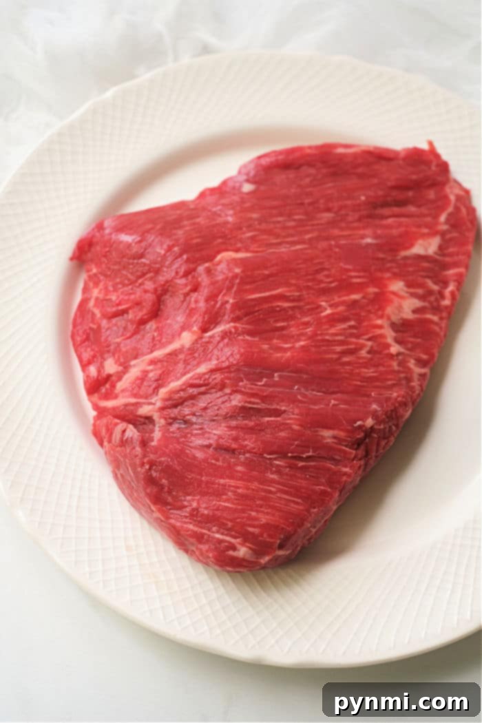 Flavor-Packed Air Fryer Dry Rub Flank Steak 4 A raw flank steak rests invitingly on a white plate, just waiting to be transformed into a succulent dish in the air fryer.