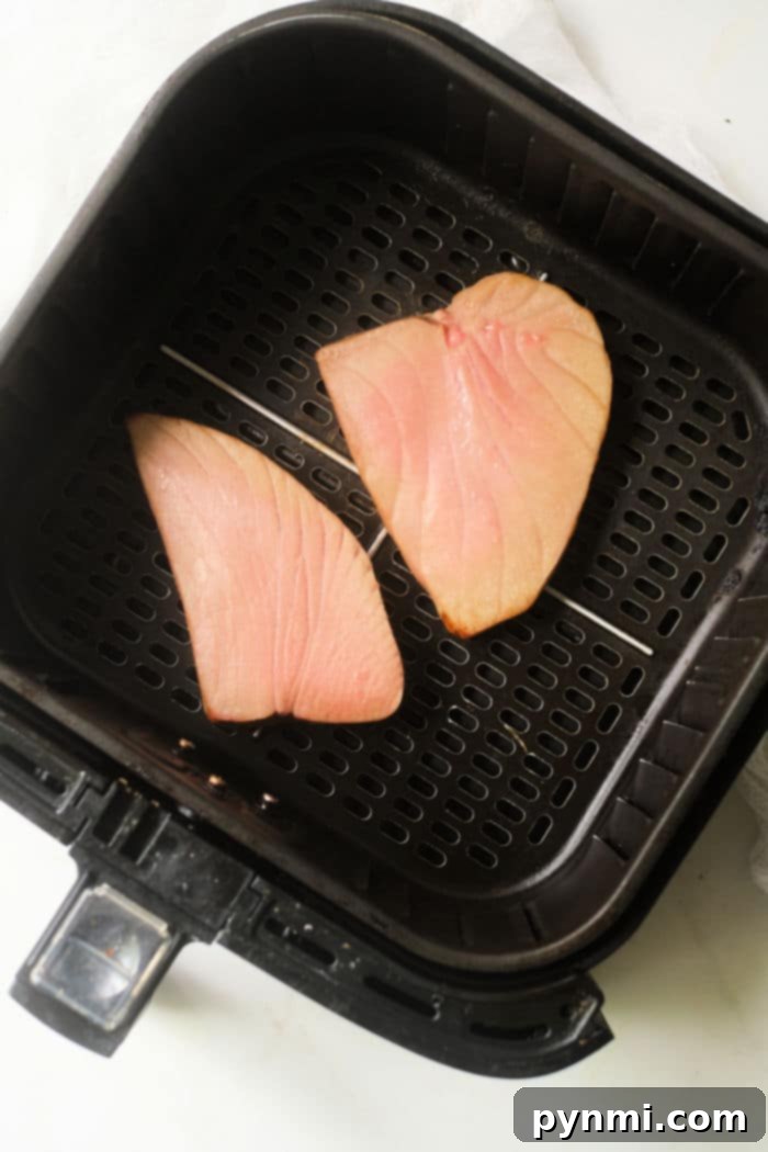 Sliced air fryer tuna steak garnished with sesame seeds and green onions on a white plate.