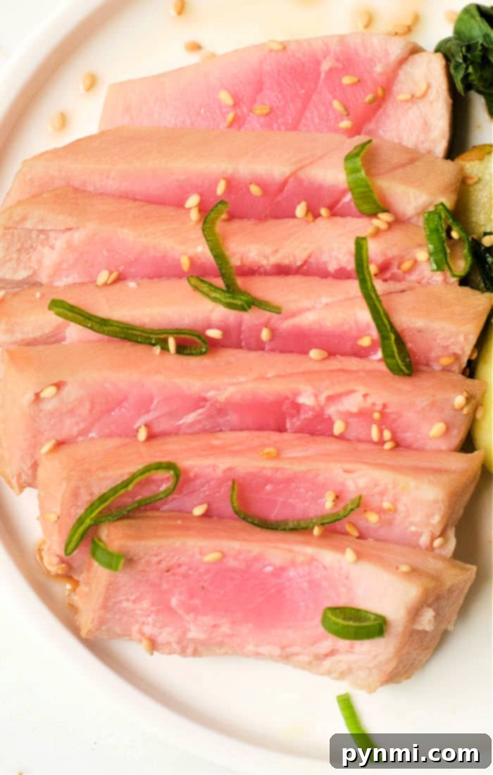 A top-down view of an air fryer basket with two raw tuna steaks, seasoned and ready for cooking.