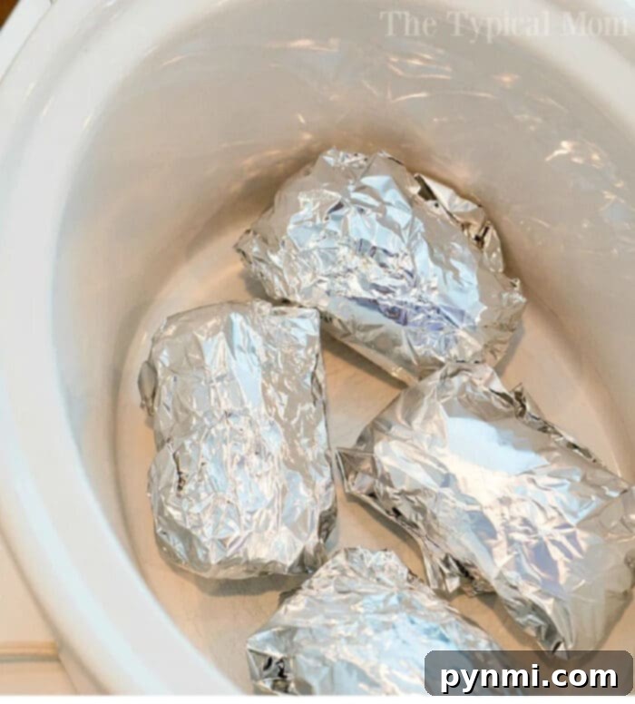 Perfect Slow Cooker Baked Potatoes 3 Slow cooker Baked Potatoes in Foil, neatly wrapped and ready for cooking.