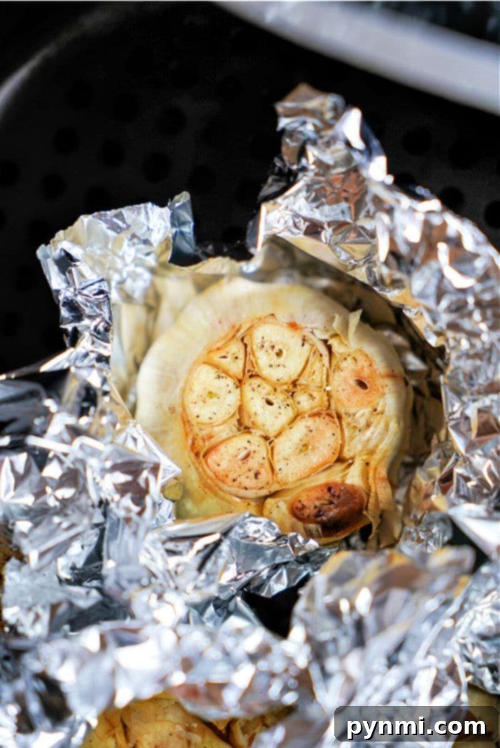 Golden brown roasted garlic bulbs in an air fryer basket, ready to be enjoyed.