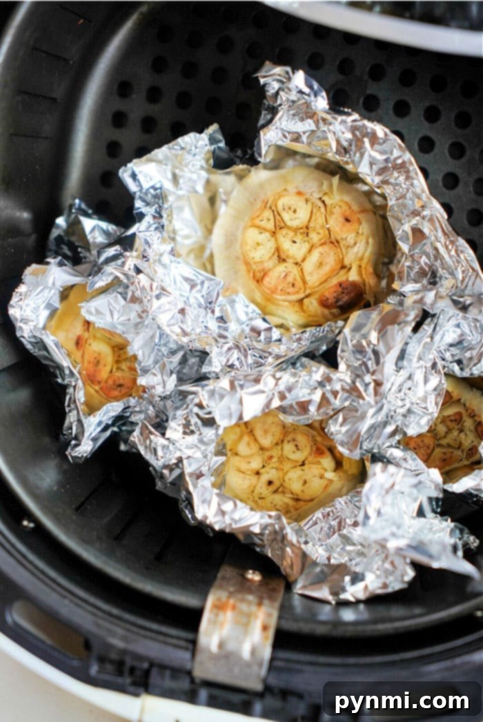 Perfectly roasted garlic bulbs with golden-brown tops, removed from the air fryer.