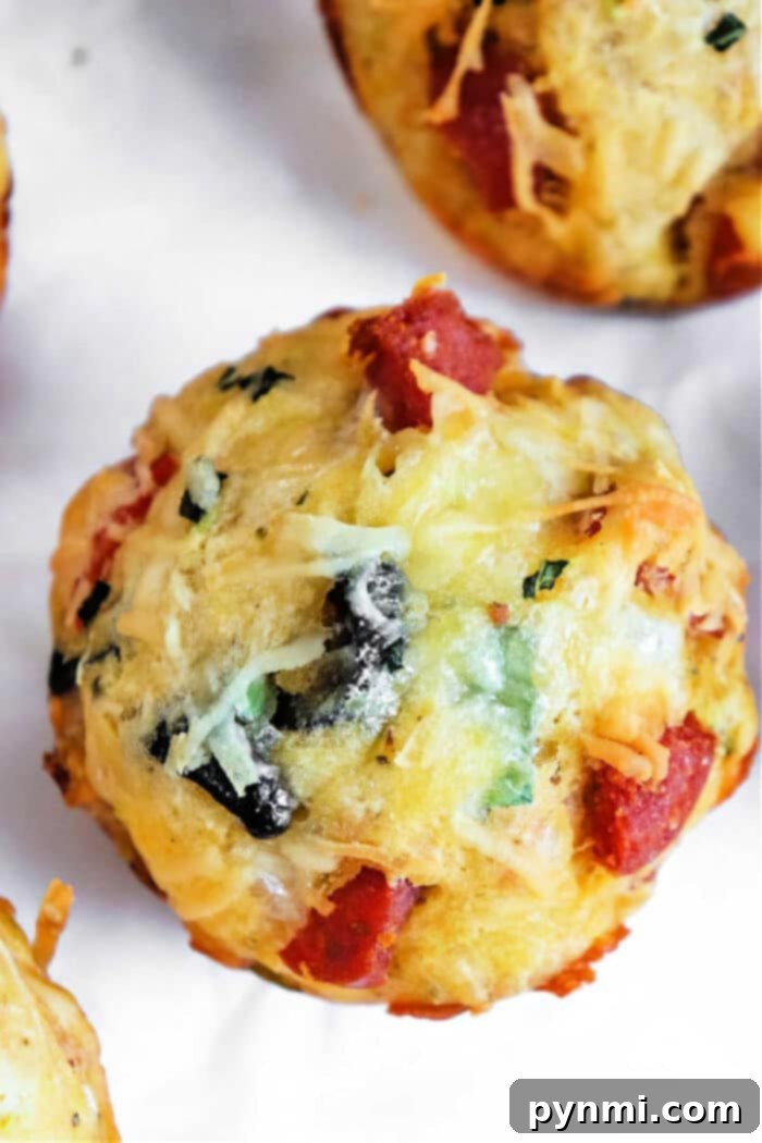 Savory Pizza Bites 2 Freshly baked pizza muffins with visible pepperoni and herbs, arranged enticingly on a cooling rack.