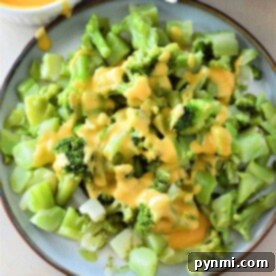 Chopped frozen broccoli covered in melted cheese sauce, perfectly prepared in an Instant Pot, served on a round plate.