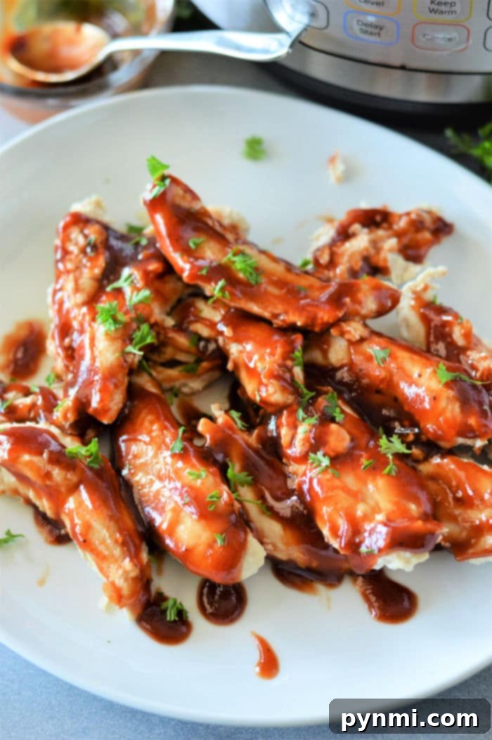 No Thaw Instant Pot Chicken Tenders 2 Frozen Chicken Tenders Instant Pot - Plate of glazed chicken pieces garnished with fresh herbs sits invitingly, as an Instant Pot hums in the background.