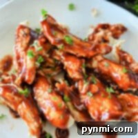 Plate of glazed chicken pieces garnished with fresh herbs sits invitingly, as an Instant Pot hums in the background, ready for its next batch of delicious frozen chicken tenders.