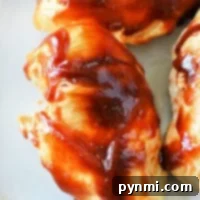 Tender chicken breasts cooked to perfection in an instant pot, covered with a rich barbecue sauce, are served on a pristine white plate.