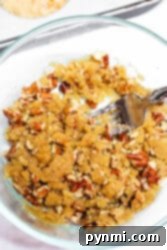 Bowl of crumbly streusel topping with pecans and a fork, perfect for your next sweet potato muffin recipe.