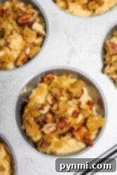 Close-up of muffin tin with unbaked sweet potato muffins topped with crumbly pecan streusel.