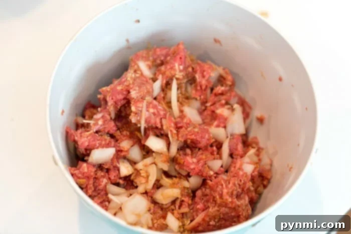Easy Weeknight Meatloaf 3 Hands mixing meatloaf ingredients in a large bowl