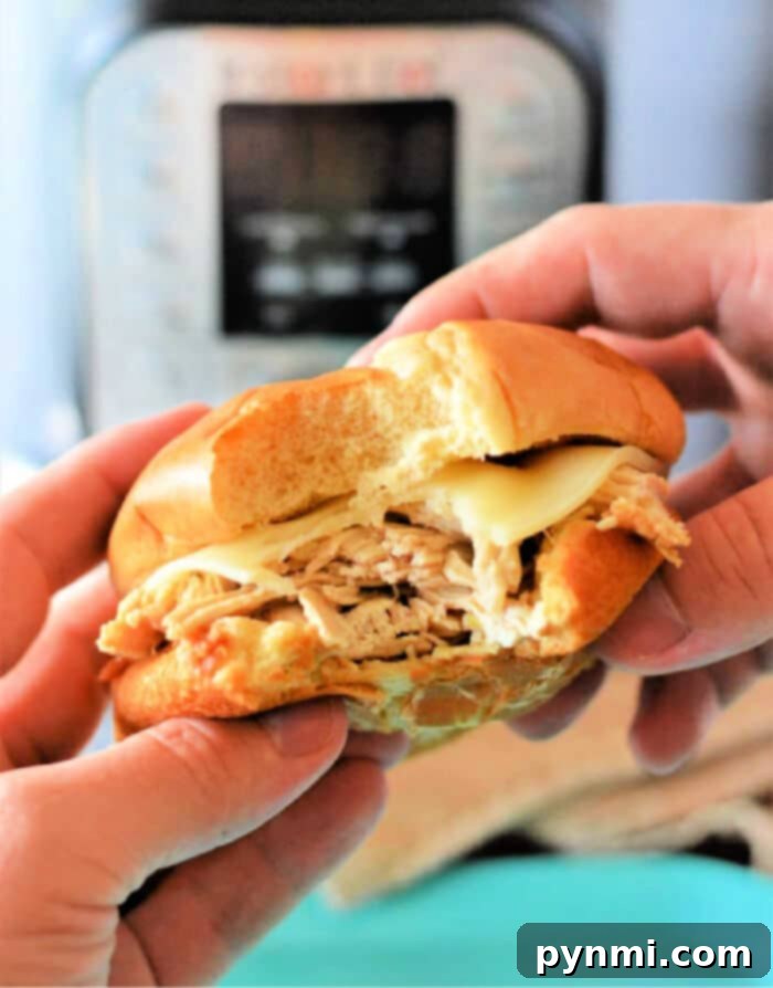 Easy Instant Pot Mississippi Chicken 2 Hands holding a sandwich with shredded Mississippi chicken seasoning in front of an Instant Pot.