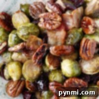 A delightful bowl of roasted Brussels sprouts, enhanced with pecans, cranberries, and crispy bacon. These flavors can be achieved using frozen Brussels sprouts air fried to perfection for that irresistible crunch.