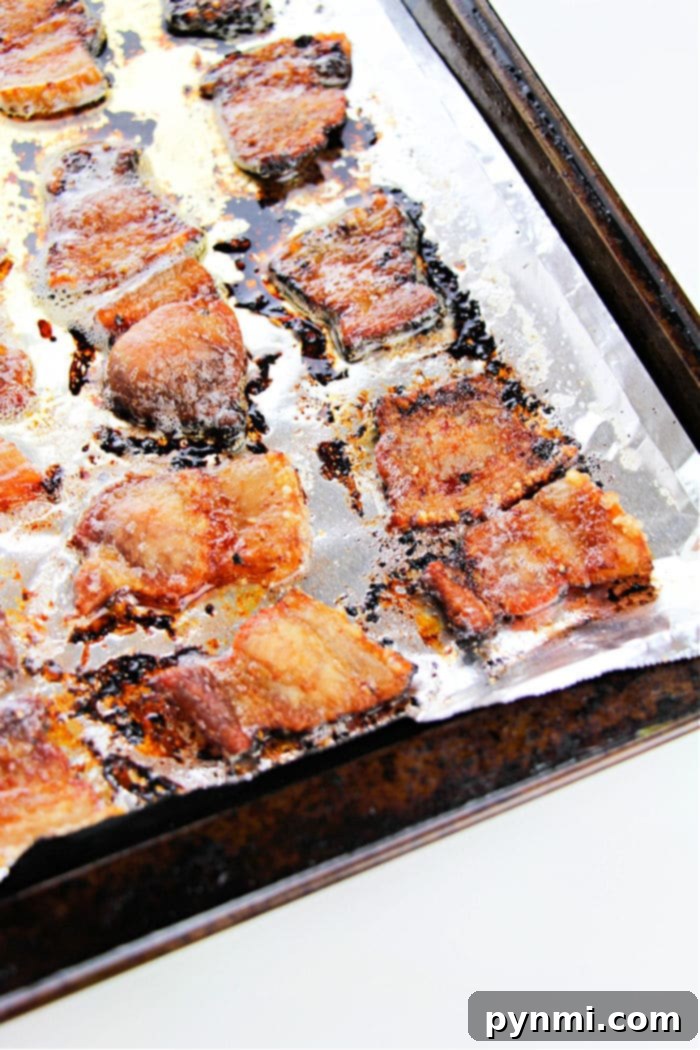 Crispy Oven-Roasted Pork Belly Perfection 6 Crispy pork pieces, reminiscent of how to cook pork belly in the oven, glisten on a foil-lined baking sheet.