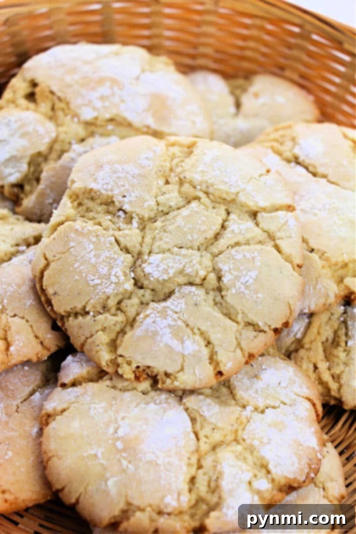 A close-up photo of a basket filled with large, cracked, and powdered sugar-coated Vanilla Cake Mix Cookies. The cookies are golden-brown with a rough, crumbly texture and appear freshly baked.