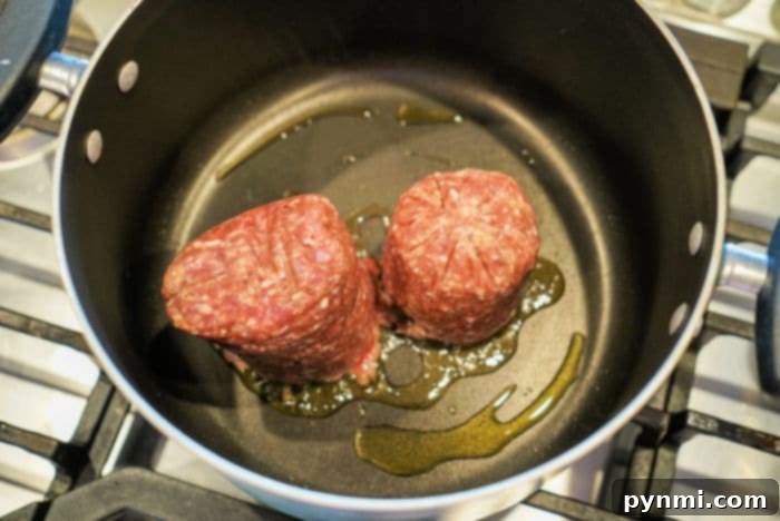 Close-up of browned ground beef with diced onions in a large skillet, ready for the next steps of the casserole.