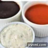 Three bowls of dipping sauce for chicken wings: buffalo, barbeque, and creamy herb