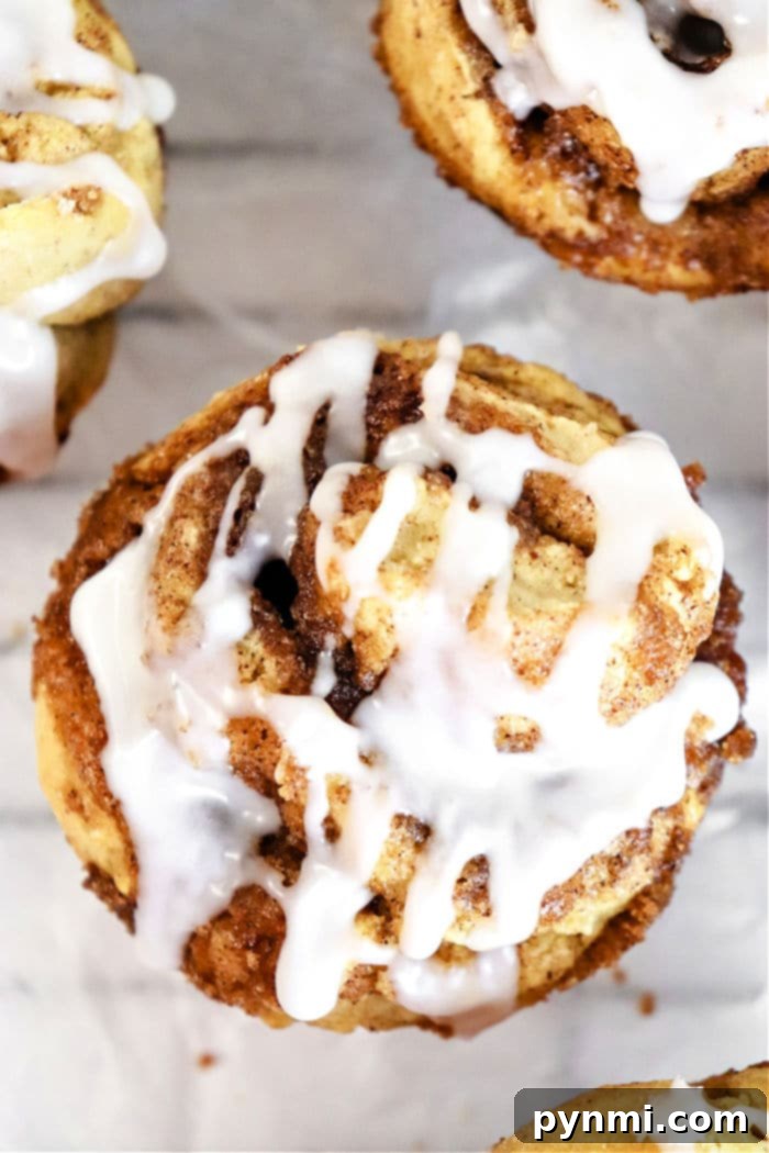 Sweet Cinnamon Swirl Muffins 2 Delicious cinnamon roll muffins drizzled with sweet icing, ready to be enjoyed.