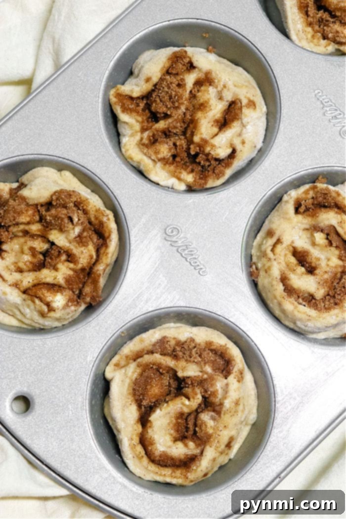 Sweet Cinnamon Swirl Muffins 5 A batch of freshly baked homemade cinnamon roll muffins on a wire rack, glistening with sweet white icing.