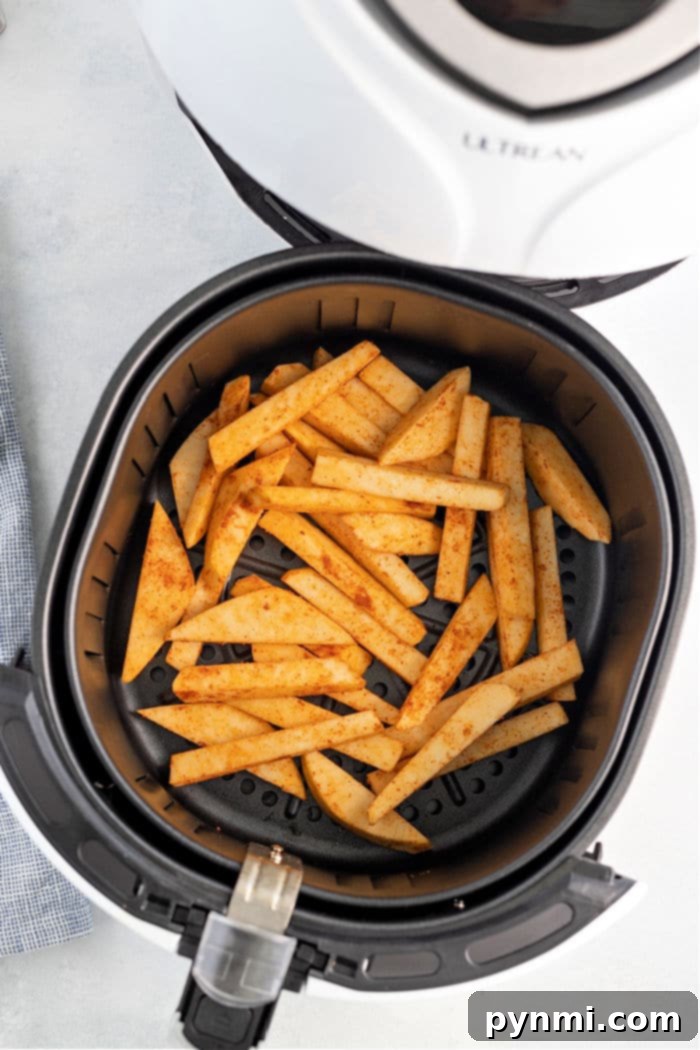 Crispy Turnip Fries 5 The image shows a black air fryer basket filled with seasoned, cut potato fries. The air fryer is open, revealing the fries inside. The appliance brand "Ultrean" is visible on the open lid. On a light-colored surface, these delicious fries could easily be swapped for turnip fries to enjoy a unique twist.