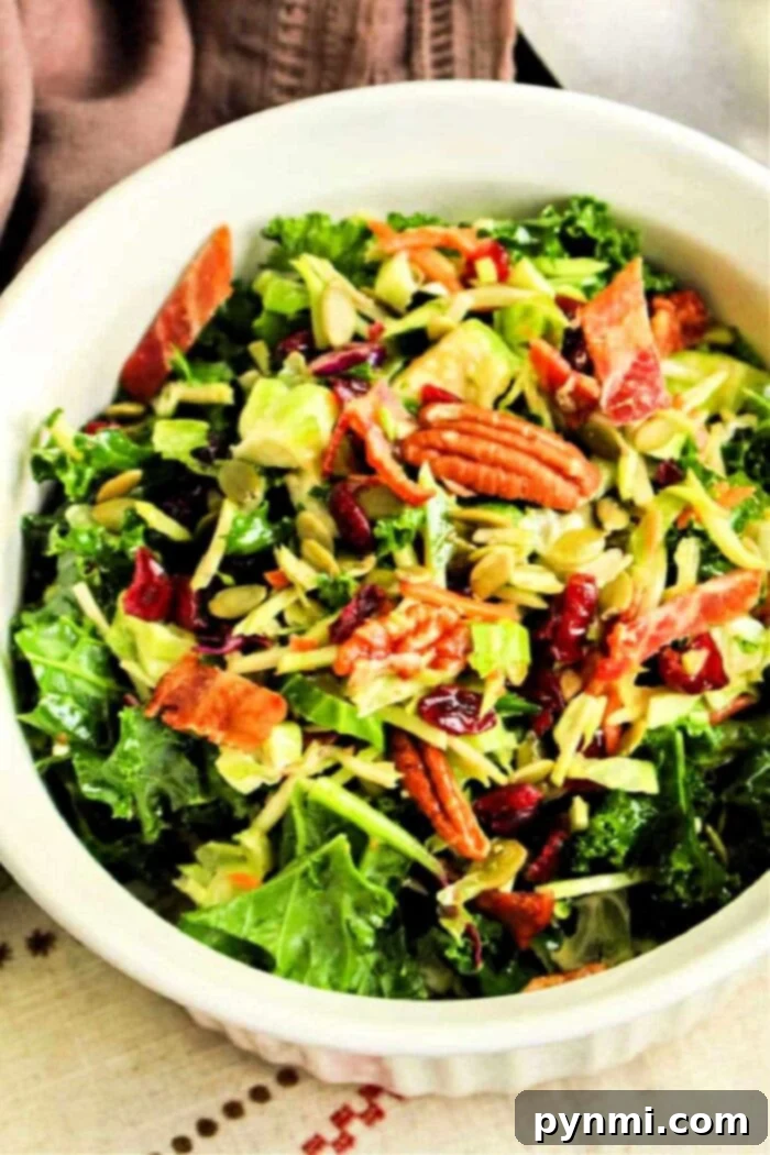 A beautifully presented shredded Brussels sprout salad with kale, cranberries, nuts, and bacon, ready to be served.