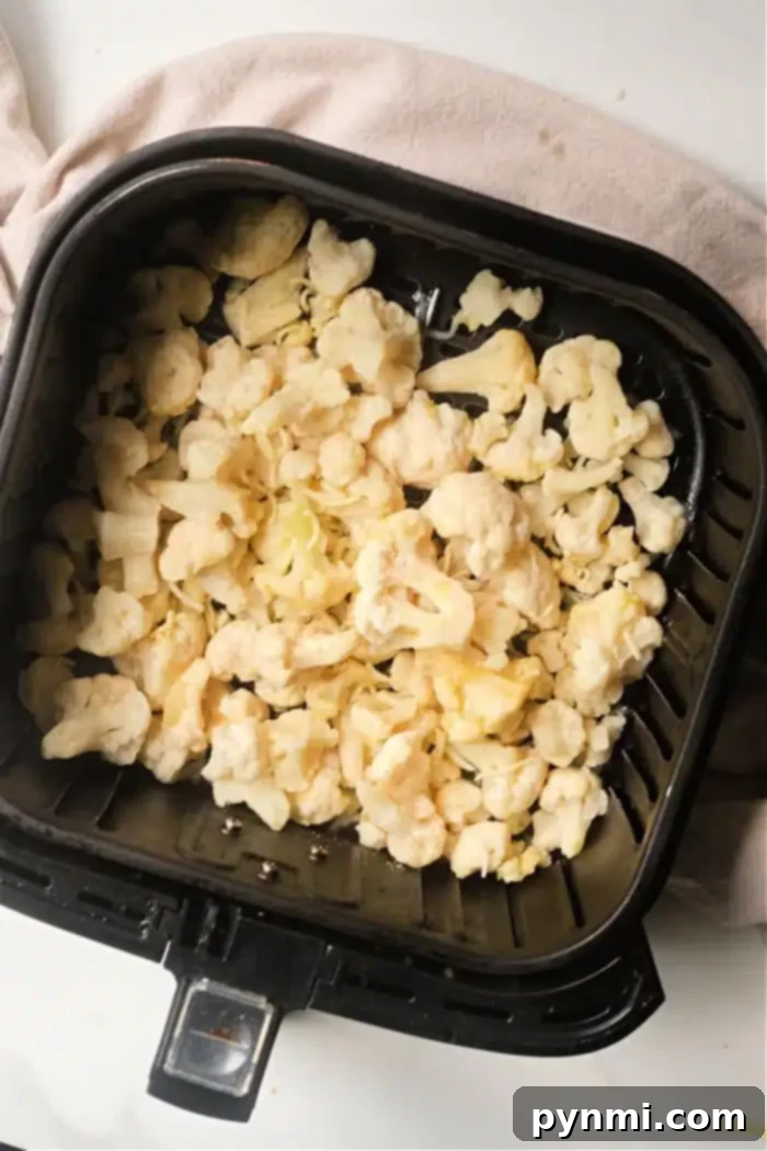 Perfectly Tender Air Fried Frozen Cauliflower 6 Golden-brown frozen cauliflower florets in an air fryer basket, ready to be served.