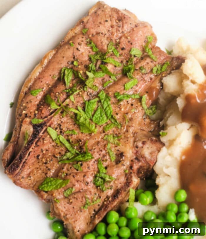 Air Fryer Lamb Chops: Your New Favorite Dinner 11 ninja foodi lamb chops in the air fryer, seasoned with herbs, served alongside creamy mashed potatoes, rich gravy, and a side of peas on a white plate.