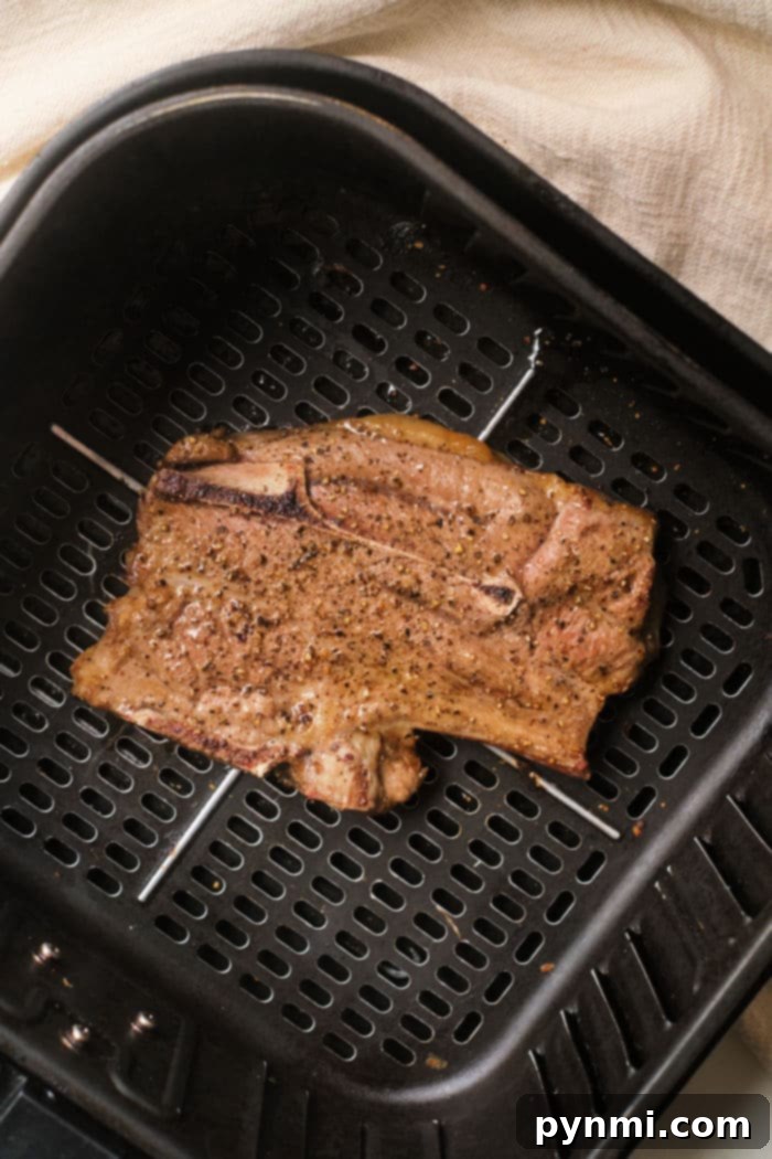 Air Fryer Lamb Chops: Your New Favorite Dinner 8 Perfectly cooked lamb chops in an air fryer basket, set against a light fabric background.