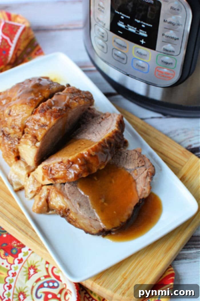 Fall-Apart Tender Instant Pot Rump Roast 2 Sliced roast beef with gravy, made from a tender instant pot rump roast, served on a white plate next to an Instant Pot on a wooden board.